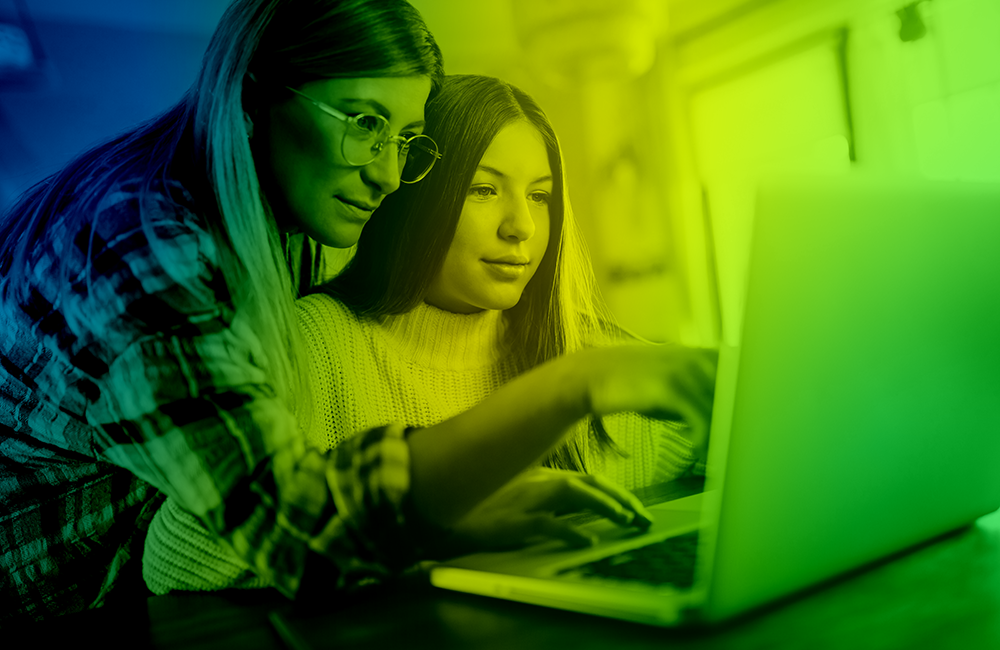 A gen alpha girl with her mother looking together at a laptop screen