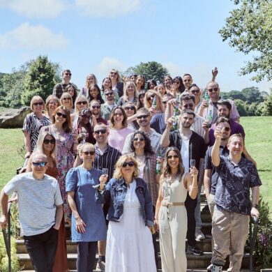 The WPR team standing on steps on a sunny day and raising glasses