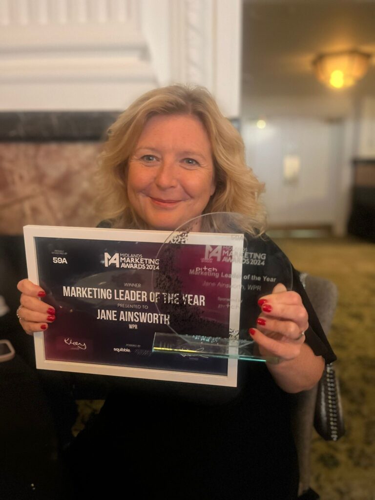 Jane holding her award and certificate as marketing leader of the year