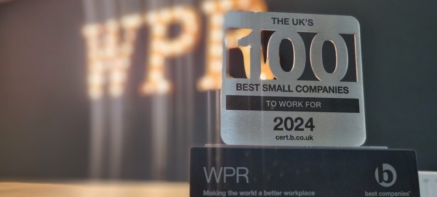 UK 100 Best Small Companies to Work For 2024 trophy in front of WPR logo in lightbulbs